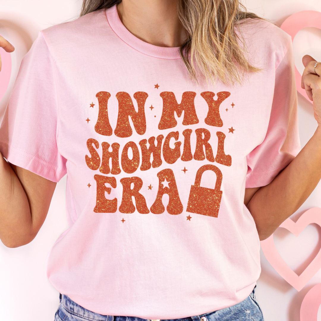 Person wearing a pink t-shirt with 'In My Showgirl Era' text in orange.