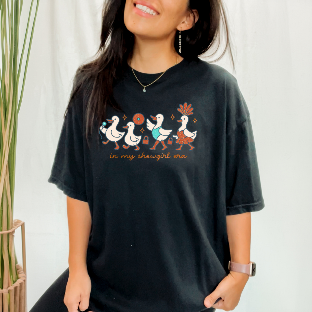 Person wearing a black t-shirt with colorful duck design and text.