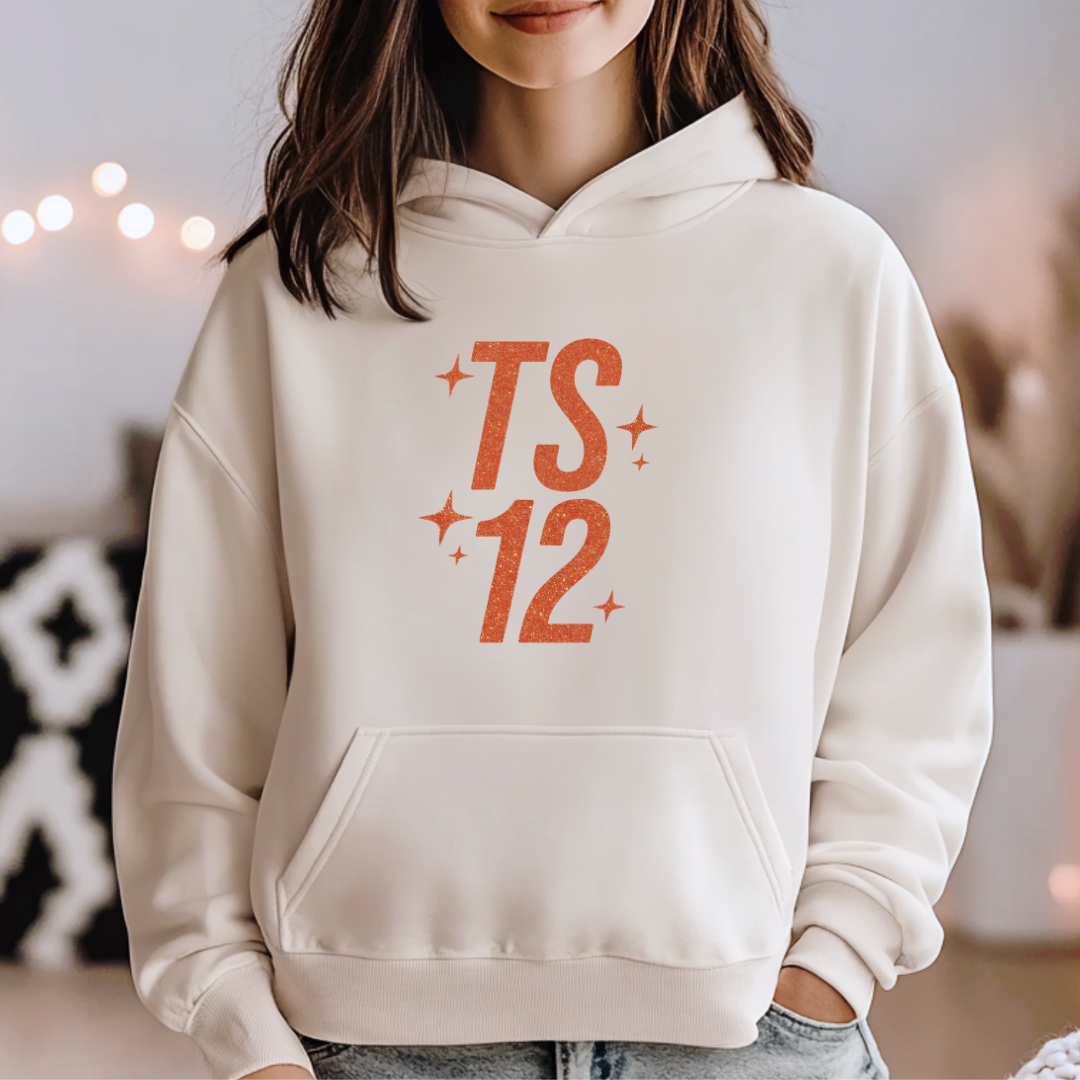 Person wearing a beige hoodie with 'TS 12' printed in orange.