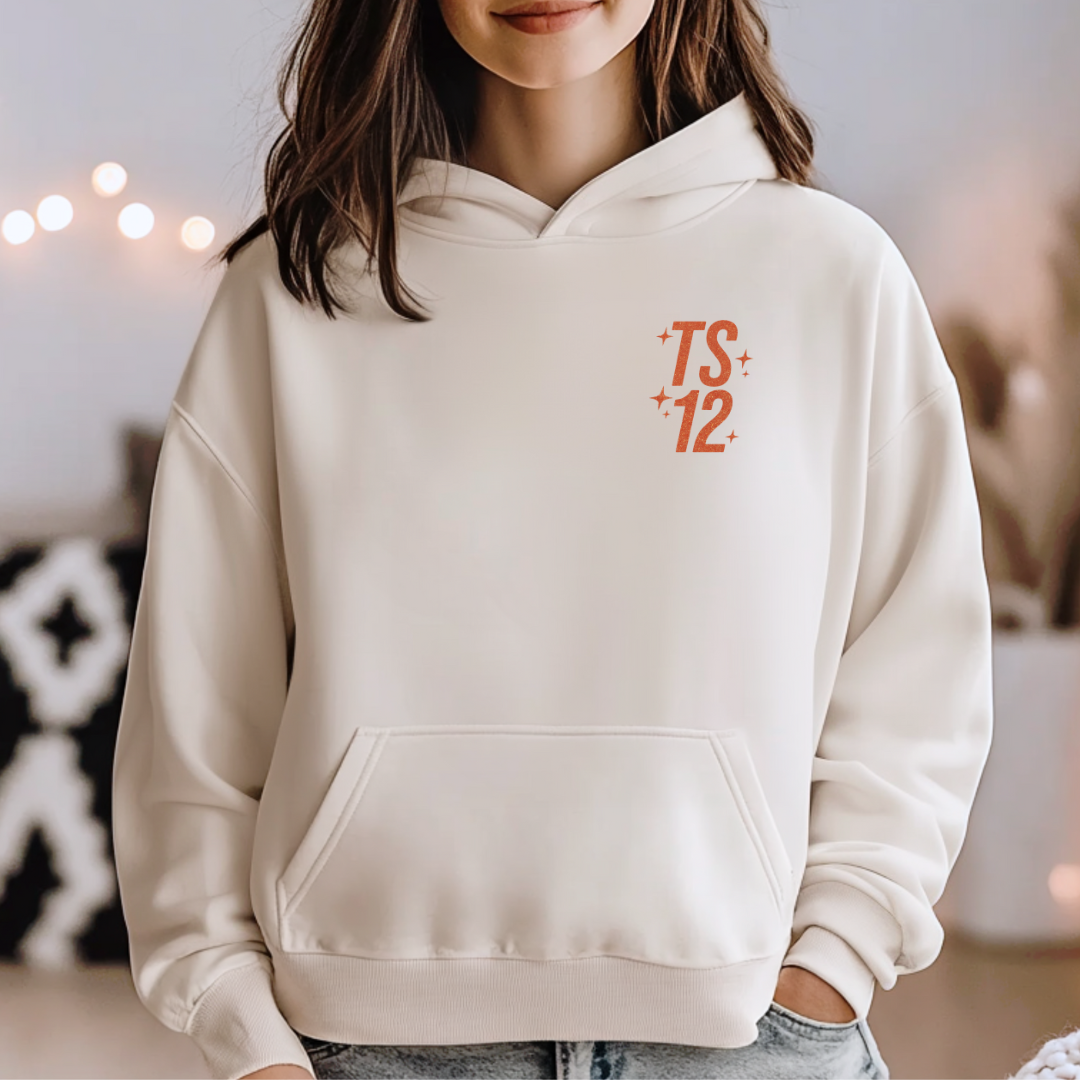 Person wearing a beige hoodie with 'TS 12' logo in orange.