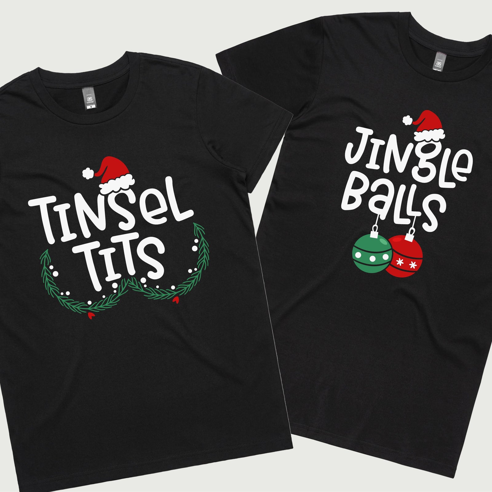 Two black t-shirts, one with the text 'TINSEL TITS' and Christmas-themed decorations, and the other with 'JINGLE BALLS' and a Christmas tree graphic. Both shirts have a festive, Christmas-themed design.