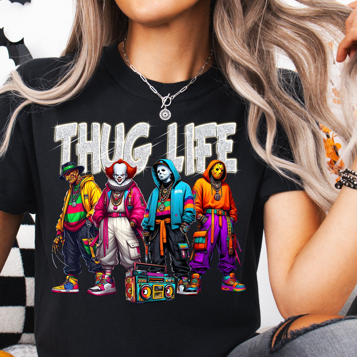 A person wearing a black T-shirt with a colorful illustration of various horror icons including Freddy Krueger, Pennywise, Michael Myers, and Jason Voorhees, and the text 'THUG LIFE'.