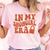 Person wearing a pink t-shirt with 'In My Showgirl Era' text in orange.
