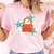 Person wearing a pink t-shirt with a colorful handbag and star design.