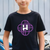 Child wearing a black t-shirt with a purple and white Huntrx logo , standing next to a bicycle.