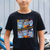 Child wearing a black t-shirt with a colorful graphic design of k-pop demon hunters, sitting outdoors.