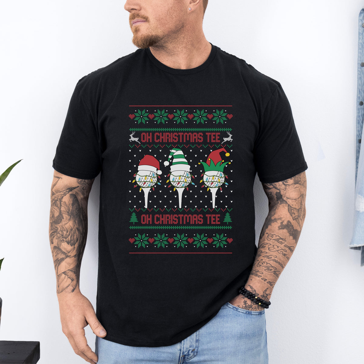 A man wearing a black Christmas-themed t-shirt with text 'Oh Christmas Tee' and decorative elements resembling Santa Claus and a Christmas tree.
