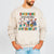 Beige sweatshirt with colorful graphic and text 'Everyone Communicates Differently' worn by a person on a light gray background.