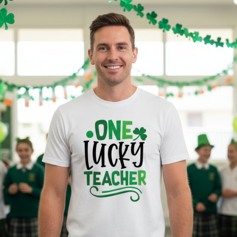 White t-shirt with 'One Lucky Teacher' text in green and black on a white background