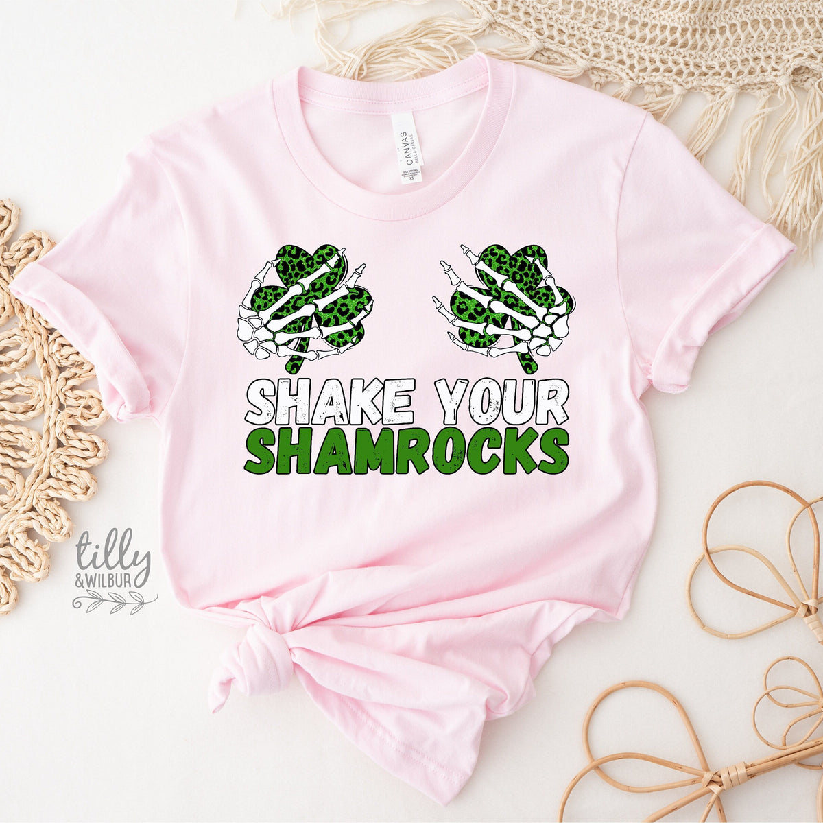 Pink baby onesie with shamrock design and 'Shake Your Shamrocks' text on a textured surface.