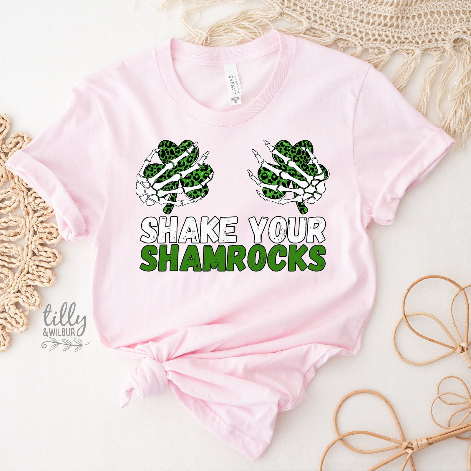 Pink baby onesie with shamrock design and 'Shake Your Shamrocks' text on a textured surface.