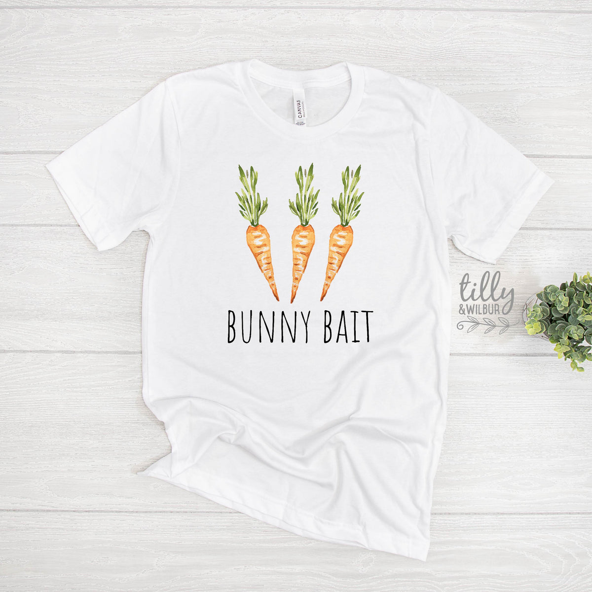White t-shirt with 'Bunny Bait' text and carrot graphics on a light wooden surface.