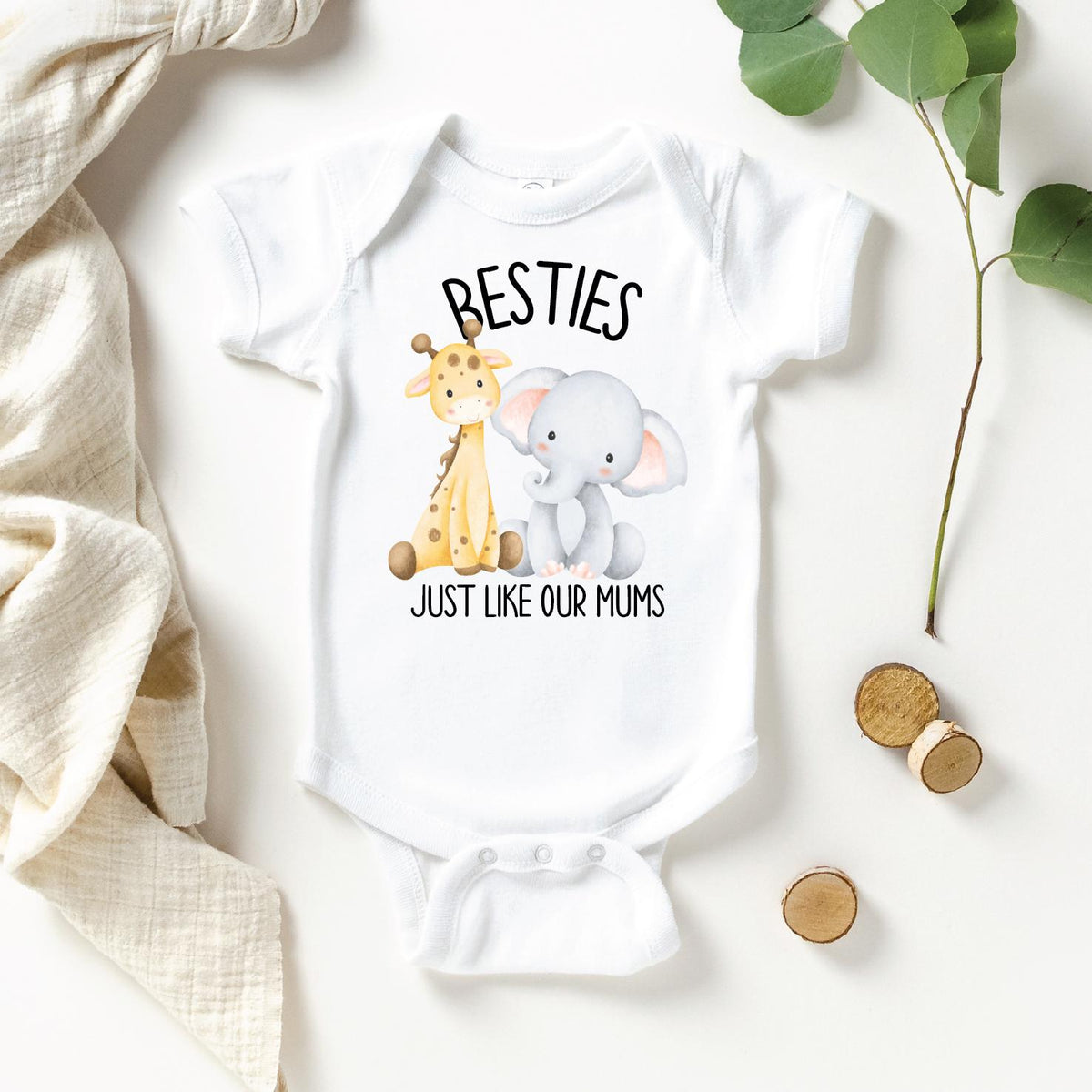 A white baby onesie with a printed design of a giraffe and an elephant, along with the text &amp;quot;Besties Just like our Mums&amp;quot;.