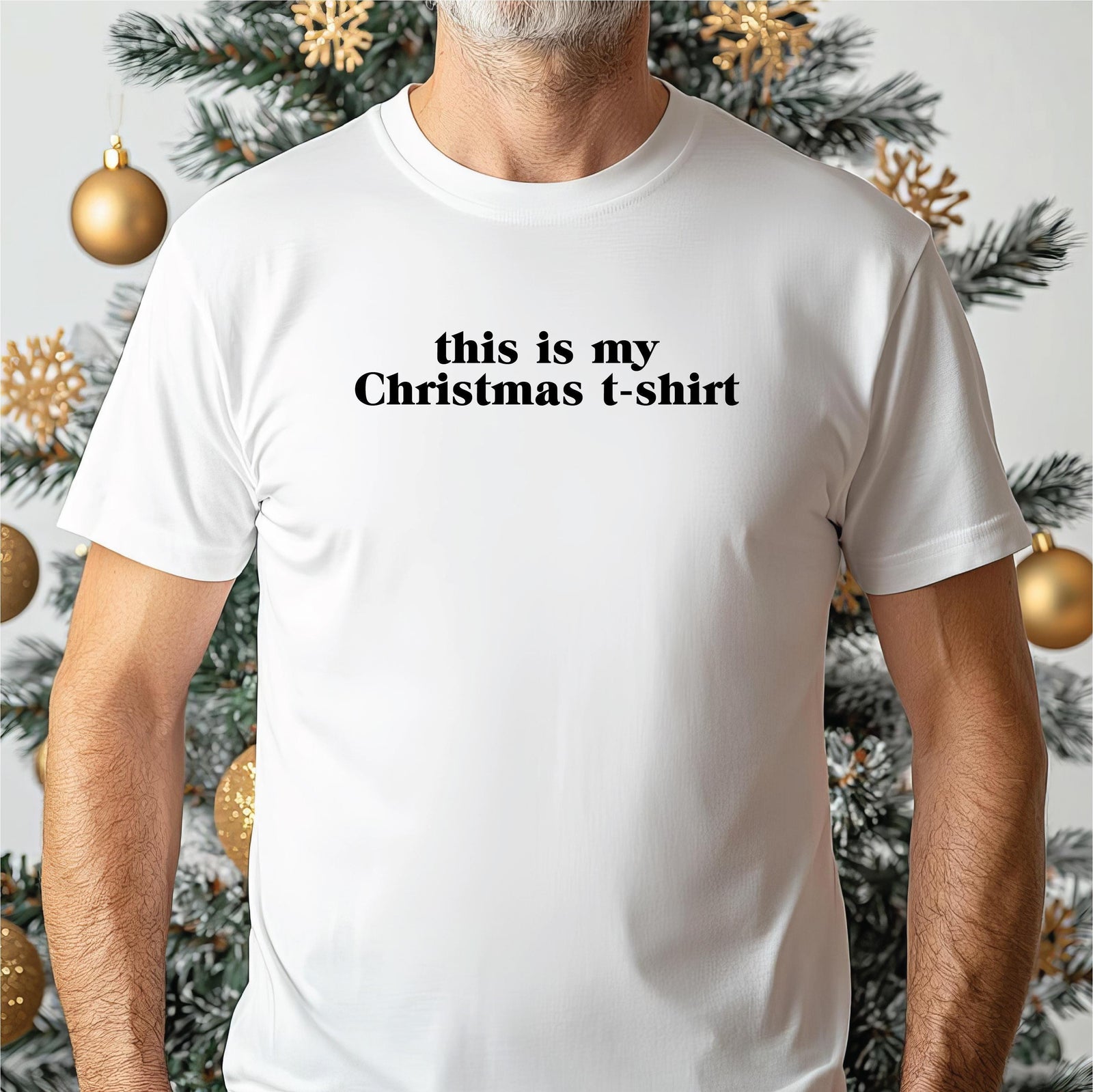 A woman wearing a pink t-shirt with the text "this is my Christmas t-shirt" stands in front of a Christmas tree and a beach.
