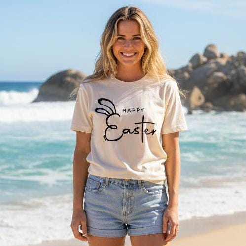 Minimalist Happy Easter bunny t-shirt in black print on natural beige shirt worn by woman on beach