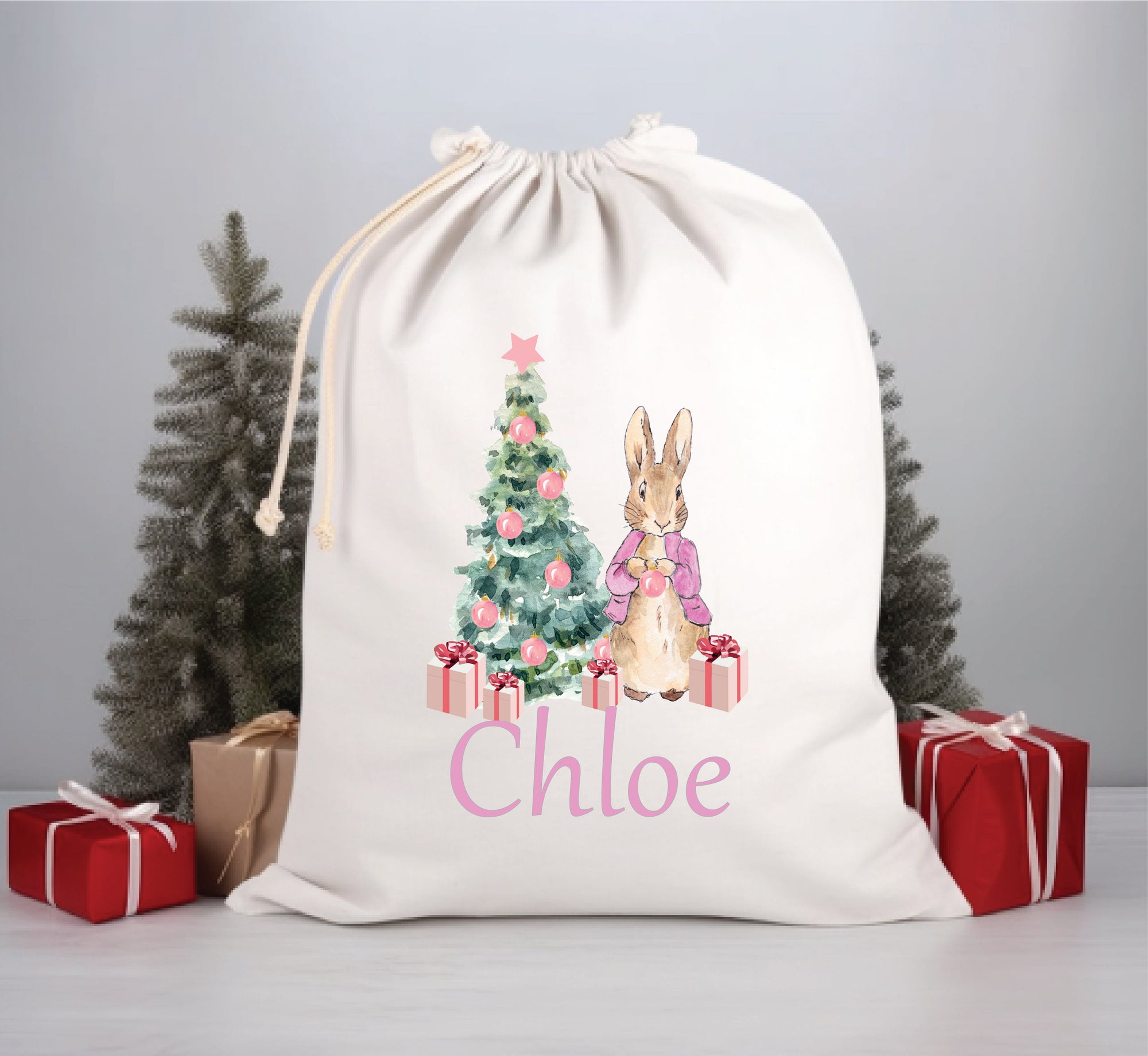 A white Santa sack with a floral pattern, featuring an illustration of a rabbit, a Christmas tree, and presents. The name 'Chloe' is printed in pink on the front.