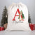 A white Santa sack with a red initial and the name 'Archie', featuring an illustration of Peter Rabbit, presented alongside Christmas trees and presents.