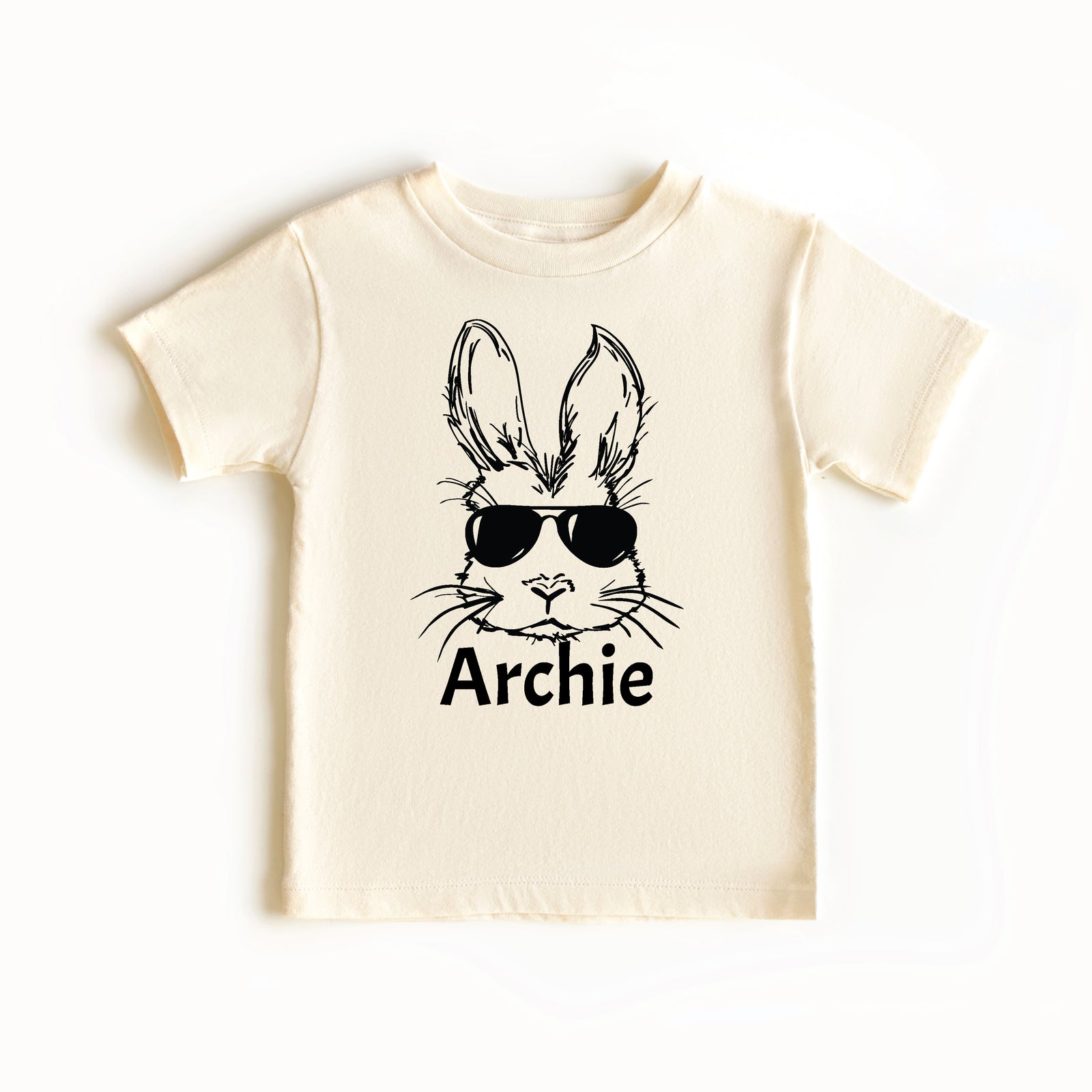 Beige t-shirt with a graphic of a rabbit wearing sunglasses and the name 'Archie' on a white background